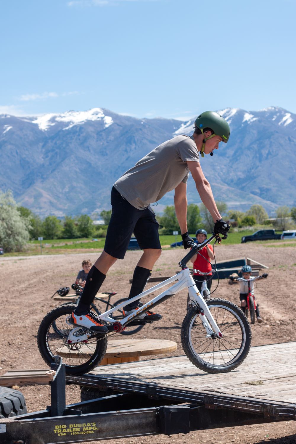 A trials rider balanced on an obstacle with mountains behind